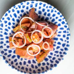 Ensalada de tomate de temporada con cebolleta fresca y aceite de ajo